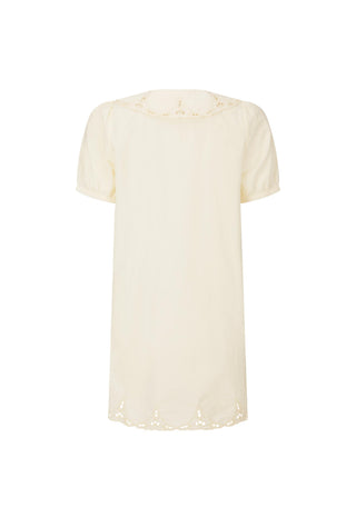 A woman outdoors wearing a cream-colored short-sleeve button-front dress with eyelet trim and a matching belt