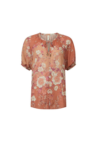 A woman modeling a short-sleeve button-up blouse with a peach