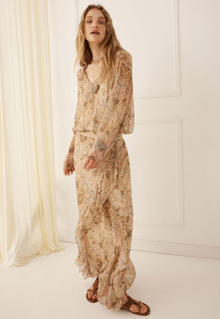 A woman modeling a long-sleeved maxi dress with a beige and brown paisley pattern