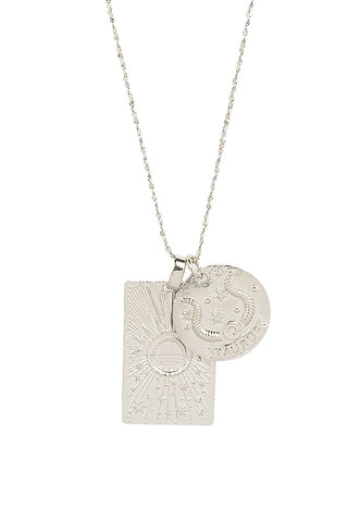 Close up front view of Spell’s Taurus Stargazer Zodiac Necklace charms. One charm is of a rectangular shape and features a sun with stars while the other charm is circular and features the Zodiac label and icon.