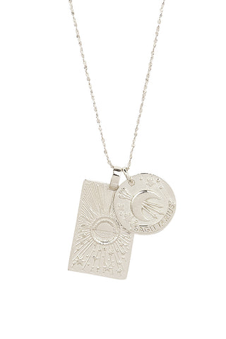 Close up front view of Spell’s Sagittarius Stargazer Zodiac Necklace charms. One charm is of a rectangular shape and features a sun with stars while the other charm is circular and features the Zodiac label and icon.